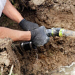 Person repairing leaking underground pipe.