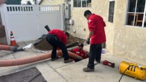 Trenchless sewer repair : Technicians removing attic insulation with vacuum hose outside a home in Los Angeles, CA.